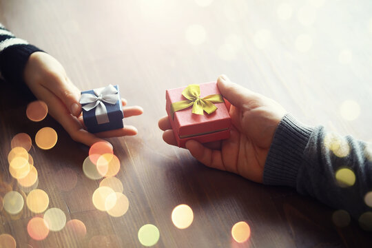 Male female hands holding gift box for birthday on wooden background. Fathers day valentine day, Christmas, New Year. Congratulations background.