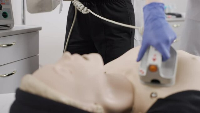 A professional nurse at a first aid course with defibrillator demonstrates work on a dummy