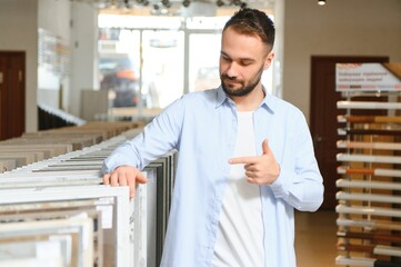 Obraz premium Young man choosing tiles at building market