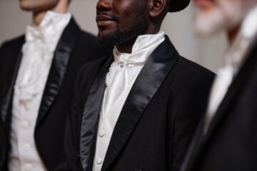 Close up of diverse group of classic gentlemen standing in row and wearing tuxedos