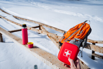 A tourist first aid kit for trekking on rough terrain, a first aid kit, a thermos with tea, a backpack in the background.