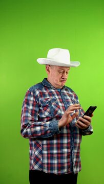Senior man in cowboy hat using smart phone and choosing goods of buying.