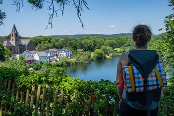 A hiker with a backpack enjoys the view of the Ulmener Maar