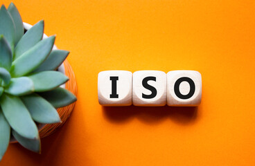 ISO standards quality control symbol. Concept word ISO on wooden cubes. Beautiful orange background...