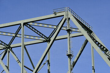 Large green metal bridge against clear blue sky.