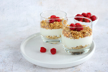 a tray with drinking glasses with oatmeal, raspberries and yogurt 