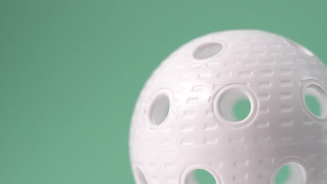 White Floorball ball close-up shot with green background