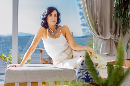 Retrato de uma linda e elegante designer de interiores de mulher madura com cabelos castanhos, sentada em um sofá posando.