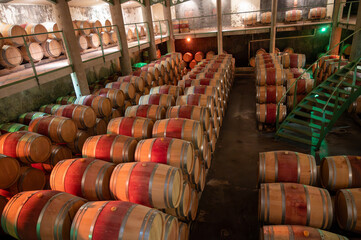 French oak wooden barrels for aging red wine in underground cellar, Saint-Emilion wine making region picking, cru class Merlot or Cabernet Sauvignon red wine grapes, France, Bordeaux