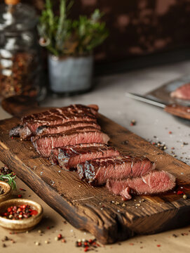 Sliced medium rare filet steak artfully presented on a rustic wooden serving board