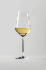 A glass filled with white wine sits on top of a wooden table