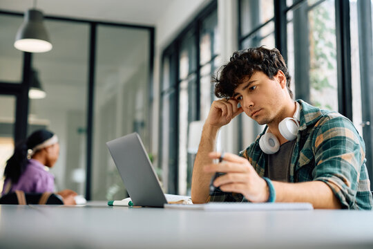 Pensive university student using laptop while learning in the classroom.