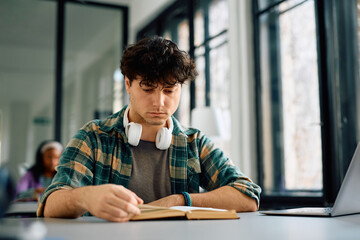 College student reading book while studying in  library.