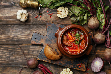 Traditional Russian and Ukrainian soup borscht with beet, beef and mushrooms served in clay bowl on...