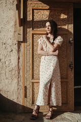 brunette girl in a dress poses at an ancient door