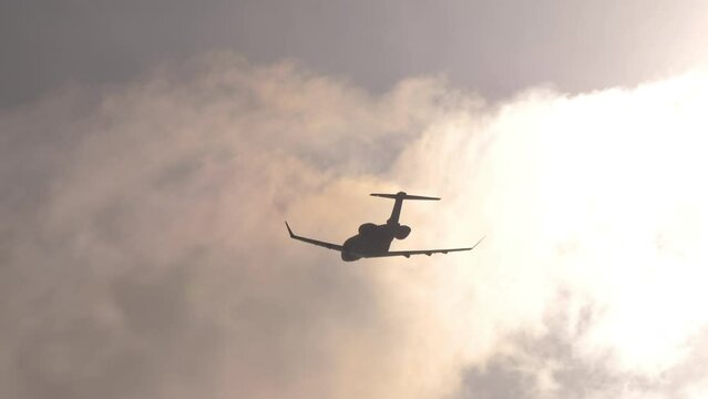 Small private plane flying in backlight, silhouette against the sun. Airplane take off, climb