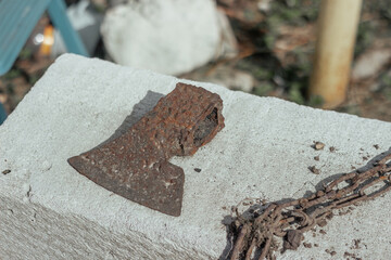 Abstract of Lumberman tools with broken rusted axe, head, chain on a gas silicate block