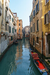 Fototapeta na wymiar Typical narrow canal surrounded by buildings with a gondola boat in Venice, Veneto, Italy