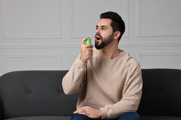 Young man using throat spray at home