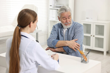 Arthritis symptoms. Doctor consulting patient with elbow pain in hospital