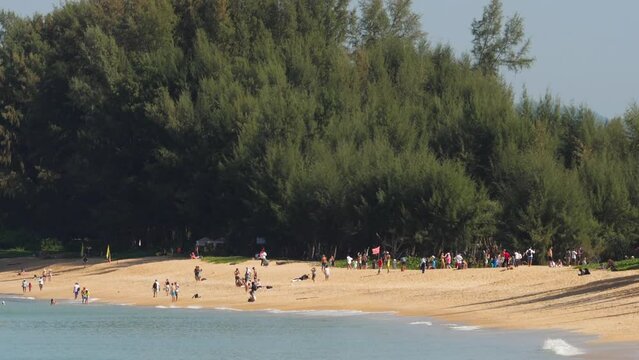 People on Mai Khao beach near the airstrip. Person looking at the flying plane above the sea, travel and active lifestyle concept