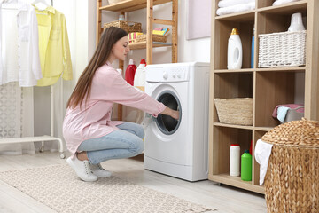 Beautiful young woman near washing machine in laundry room - obrazy, fototapety, plakaty