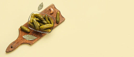 Bowl of tasty pickled cucumbers and spices on beige background with space for text, top view