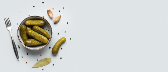 Bowl of tasty pickled cucumbers and spices on light background with space for text, top view