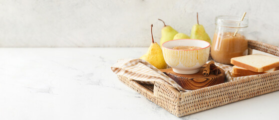 Fototapeta na wymiar Tray with tasty pear jam and toasts on light background with space for text