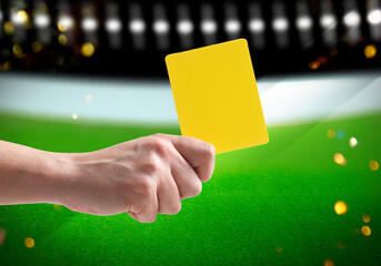 Referee holding yellow card at stadium, closeup