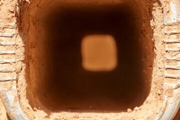 A close-up view inside a hollow, square-shaped ladder rung, revealing the textured effects of rust and wear