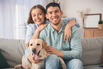 Happy young couple with Labrador dog hugging on sofa at home