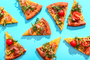 Pieces of delicious pizza with tomatoes and arugula on blue background