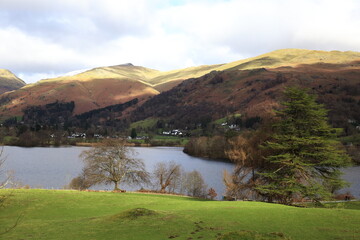 Great Rigg and Rydal Fell over Grasmere. A gloomy day in Winter and bright sun lights up the fell tops.