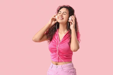 Rolgordijnen Young African-American woman with headphones listening to music on pink background © Pixel-Shot