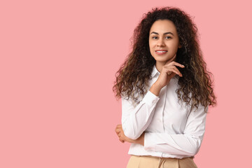 Young African-American businesswoman on pink background