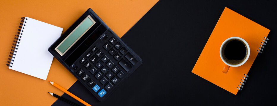 Calculator, pencil, notebook and coffee cup on the black background. Copy space. Top view.