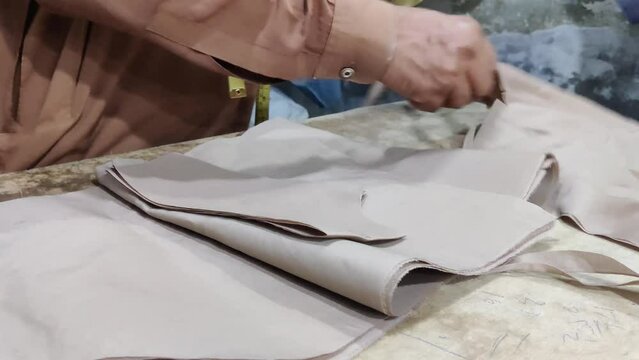 Skilled tailor meticulously cutting cotton cassock fabric with precision