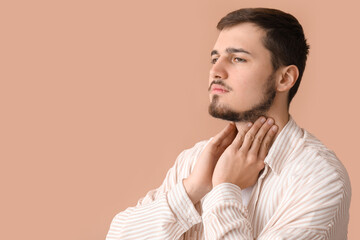 Young man with thyroid gland problem on beige background