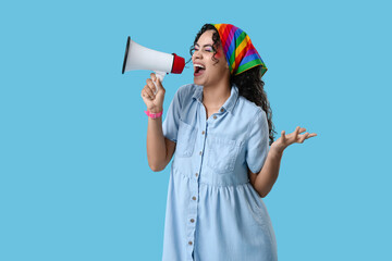 Young African-American woman with rainbow headscarf and megaphone on blue background. LGBT concept - obrazy, fototapety, plakaty
