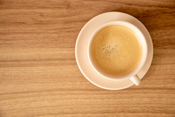 Xícara de café com leite, cor clara, bege,  madeira, pires, espaço negativo para escrita à...
