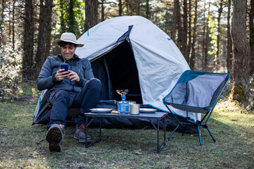 Cheerful Explorer Camper Chatting on Smartphone at Campsite