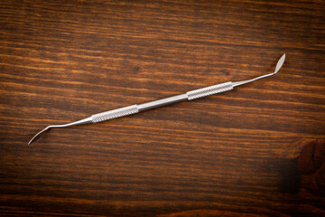Dental hygienist instrument on a dark wooden background. Learning and professionalism