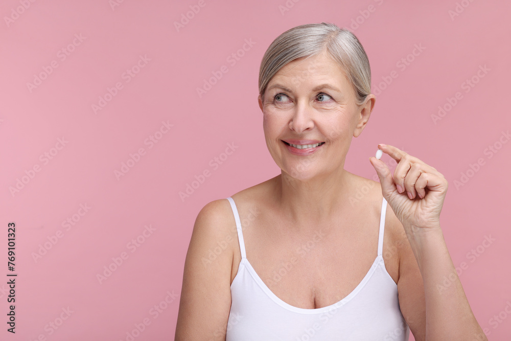 Canvas Prints Beautiful woman with vitamin pill on pink background, space for text