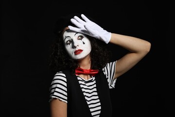 Young woman in mime costume posing on black background