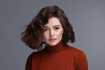 Fototapeta premium Portrait of beautiful young woman with wavy hairstyle on grey background