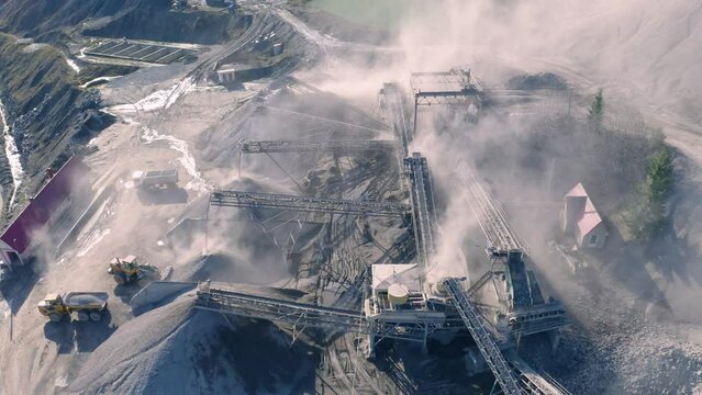 Carpathian Mountains of Ukraine, a quarry where granite sandstone is mined for the production of building materials, powerful trucks and conveyors load gravel - video from a drone
