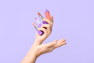 Woman's hands with different lipsticks on lilac background