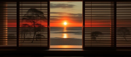 View of the sun setting as it shines through the horizontal blinds on a window, casting a warm glow in the room