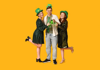 Happy friends with beer on yellow background. St. Patrick's Day celebration